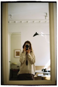 a woman taking a selfie in front of a mirror with a camera on it