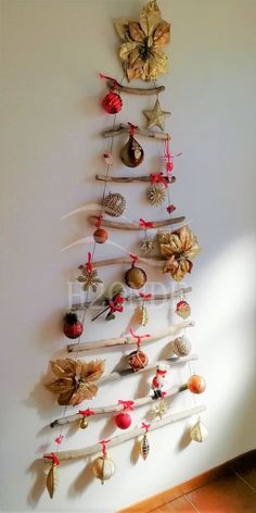 a christmas tree made out of branches with ornaments hanging from it's sides on the wall