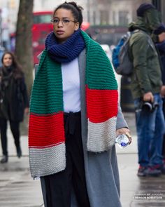 a woman is walking down the street wearing a scarf