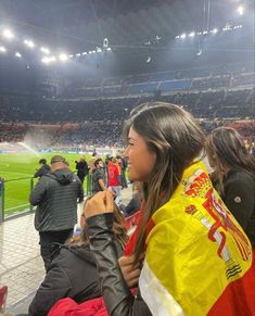 a woman is sitting in the stands at a soccer game and she has her hair combed