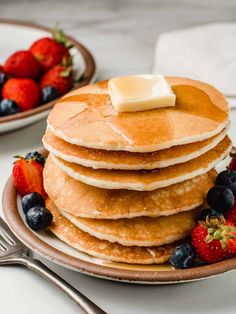 stack of pancakes with butter and berries on the side