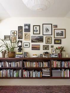 a bookshelf filled with lots of books next to a wall full of pictures