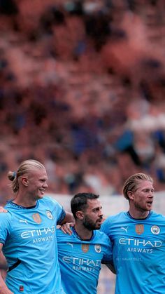 three soccer players are standing together in the middle of a field with their arms around each other