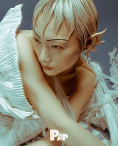 a woman with white hair and angel wings on her head is posing for the camera