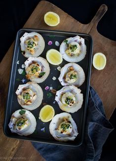 an image of some appetizers on a tray with lemon wedges and parsley