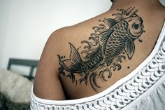 a woman's back with a tattoo on it that has a fish in the water