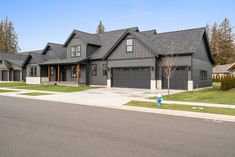 a large gray house with two garages on the street