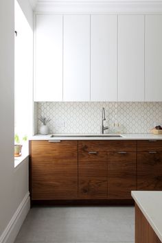 a kitchen with white walls and wooden cabinets