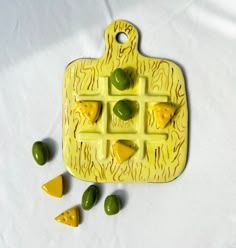 a yellow plate with green olives and cheese on it