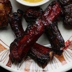 a plate with ribs and dipping sauce on it