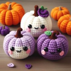 crocheted pumpkins with faces on them sitting in front of some smaller pumpkins