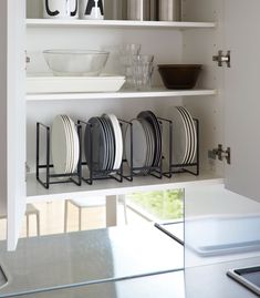 plates and bowls are sitting on shelves in the kitchen