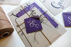 purple and white wedding stationery with twine on the table next to each other