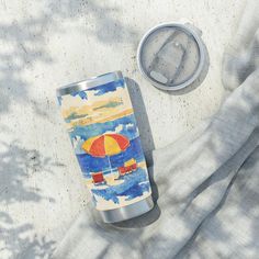 an insulated tumbler next to a can on a blanket