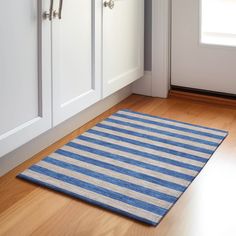 a blue and white rug sitting on top of a hard wood floor next to cabinets