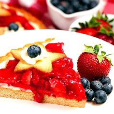 a piece of pie on a plate with blueberries and strawberries