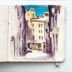 an open notebook with a drawing of a street in the middle and buildings on both sides