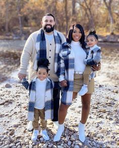 a man, woman and two children are standing on rocks in front of a river