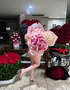 a woman holding a bouquet of flowers in front of red and white roses at a flower shop