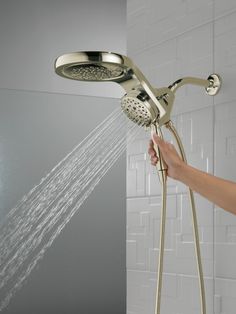 a person is holding the shower head in their hand and spraying it with water from the faucet