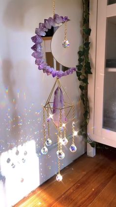 a purple wind chime hanging from a wall next to a window with beads on it