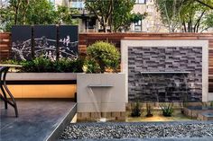 an outdoor water fountain in the middle of a patio with trees and plants around it