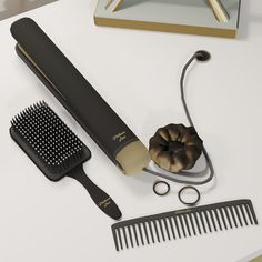 a hairbrush, comb, and other items on a white counter top with gold trimming