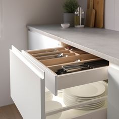 an open drawer in a kitchen with plates and utensils