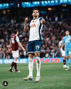 a man standing on top of a soccer field with his hand up in the air