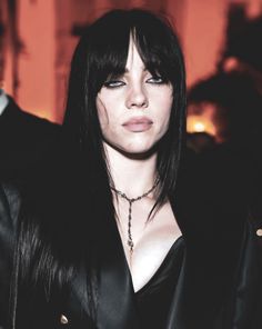 a woman with long black hair wearing a leather jacket and choker on her neck