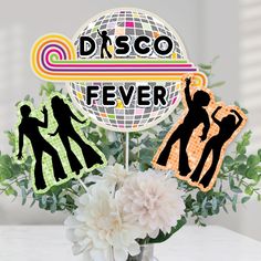 a vase filled with flowers and cutouts of dancing people on top of a disco fever sign