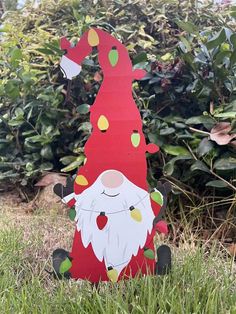 a wooden santa clause sitting in the grass