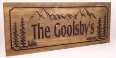 a wooden sign that says the goosly's with mountains in the background