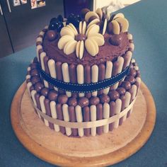 a large chocolate cake sitting on top of a wooden platter covered in candies