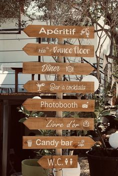 a wooden sign sitting on the side of a road next to a potted plant