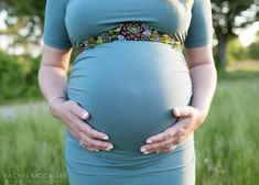 a pregnant woman is holding her belly in the grass