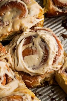 cinnamon rolls with icing sitting on top of a cooling rack