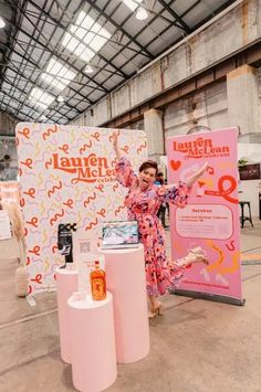 a woman standing in front of a display with pink and orange decorations on it's sides