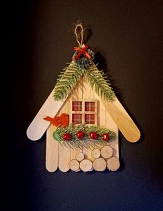 a wooden house ornament decorated with pine branches and red berries on the outside