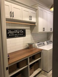 a washer and dryer in a laundry room with white cabinets on the wall