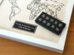 a black and white world map with buttons on the front is shown in a shadow box