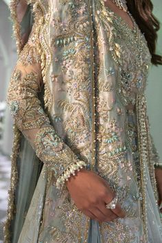 a woman in a silver and gold outfit with beads on her head, wearing an elaborate dress