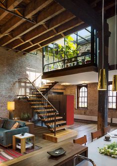 a living room filled with furniture and a spiral stair case next to a brick wall