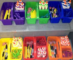 there are many plastic containers with markers and pencils in them