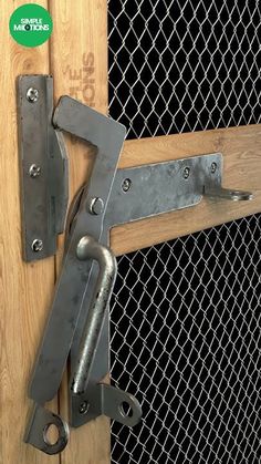 a close up of a metal latch on a wooden door with wire mesh behind it