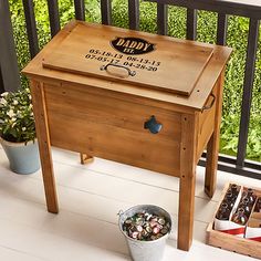 a wooden cooler sitting on top of a porch next to a potted plant