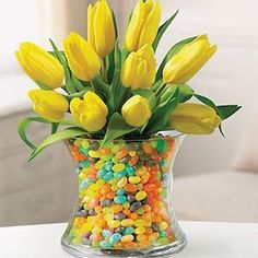 a vase filled with yellow tulips and candy