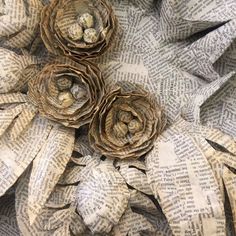 three rolled up flowers sitting on top of an old book page covered in newspaper paper