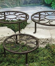 two metal tables sitting on top of grass covered ground next to a rock and planter