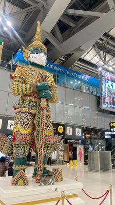 an elaborately decorated statue stands in the middle of a large airport terminal with people walking around